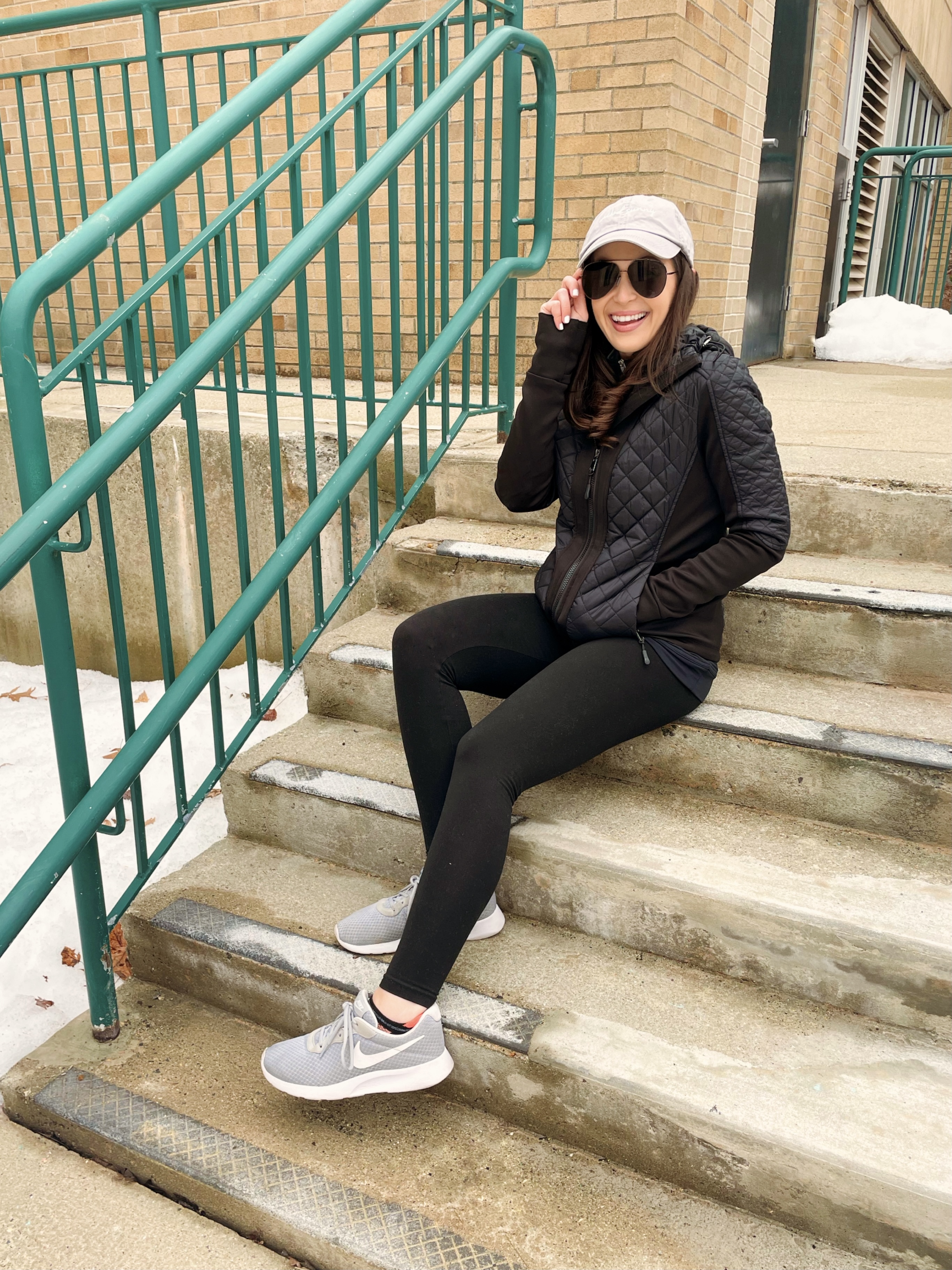 blogger on stairs fitness clothes aviator sunglasses baseball cap nike sneakers